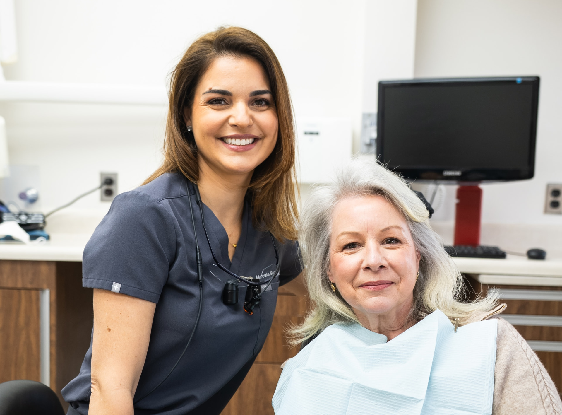A hygienist at Greenwich Dental Studio smiling beside a patient in the treatment chair