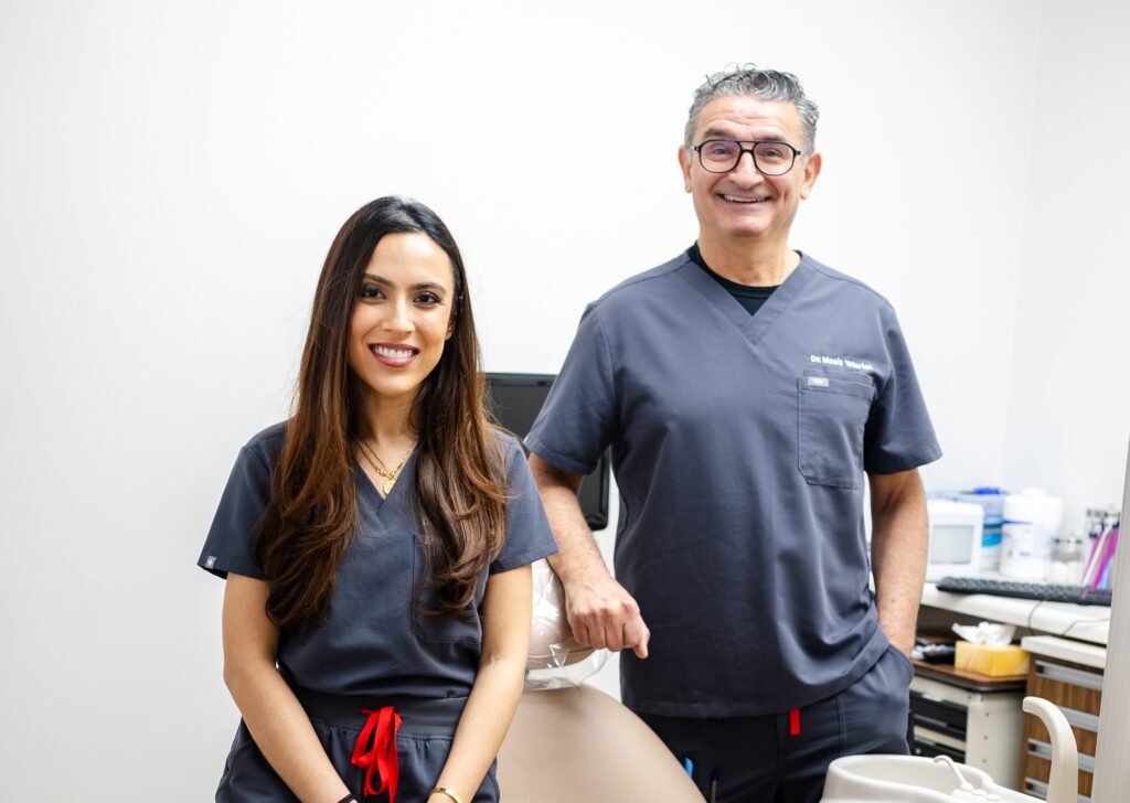 Two dental professionals in navy uniforms standing together in modern Greenwich Dental Studio treatment room space.