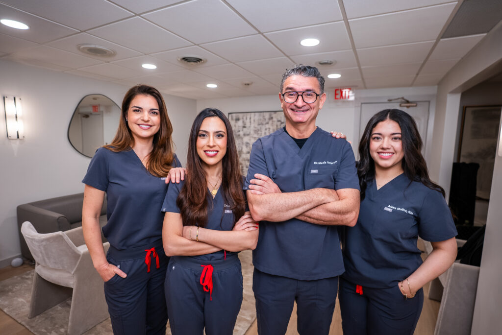 Greenwich Dental Studio team portrait with four smiling clinicians in navy uniforms inside the practice space.