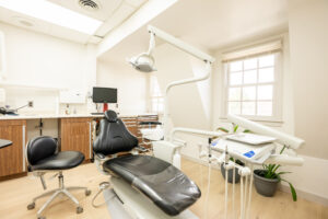 Bright dental surgery room with treatment chair, overhead light, equipment, and window at Greenwich Dental Studio.