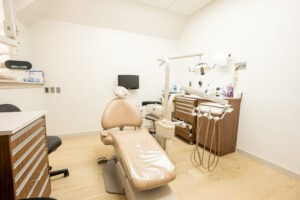 Clean dental treatment room with chair, monitor, cabinets, and warm lighting at Greenwich Dental Studio clinic.